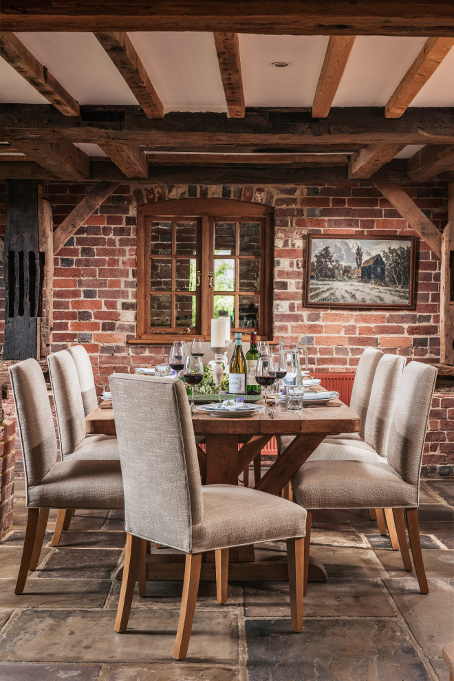 Inspiration for a mid-sized country open plan dining in Sussex with grey floor and brick walls.