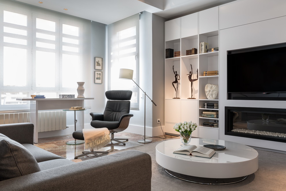 This is an example of a large contemporary formal enclosed living room in Madrid with white walls, marble floors, a ribbon fireplace and a built-in media wall.