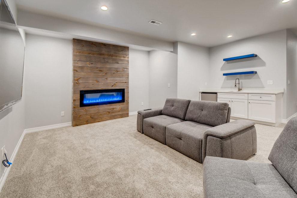 Mittelgroßes Modernes Untergeschoss mit grauer Wandfarbe, Teppichboden, Kaminumrandung aus Holzdielen und grauem Boden in Denver