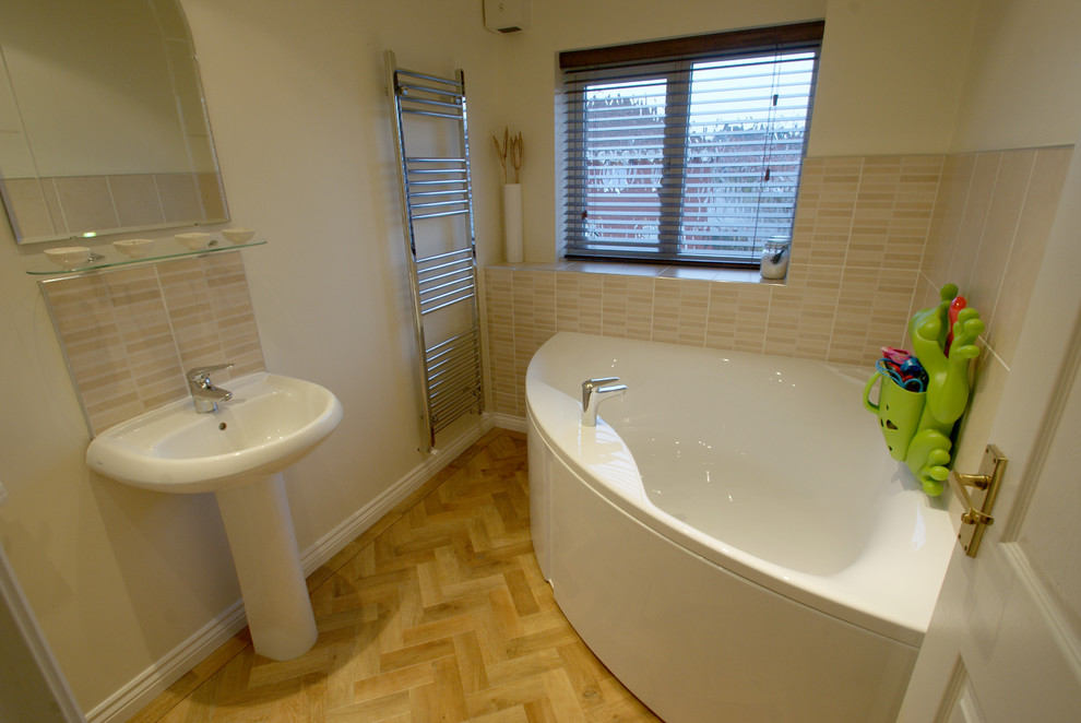 Small contemporary kids bathroom in West Midlands with white cabinets, a corner tub, a one-piece toilet, beige tile, ceramic tile, beige walls, a pedestal sink, a single vanity and a freestanding vanity.