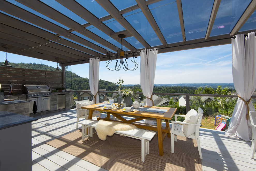 Large transitional backyard outdoor kitchen deck photo in Vancouver with a pergola