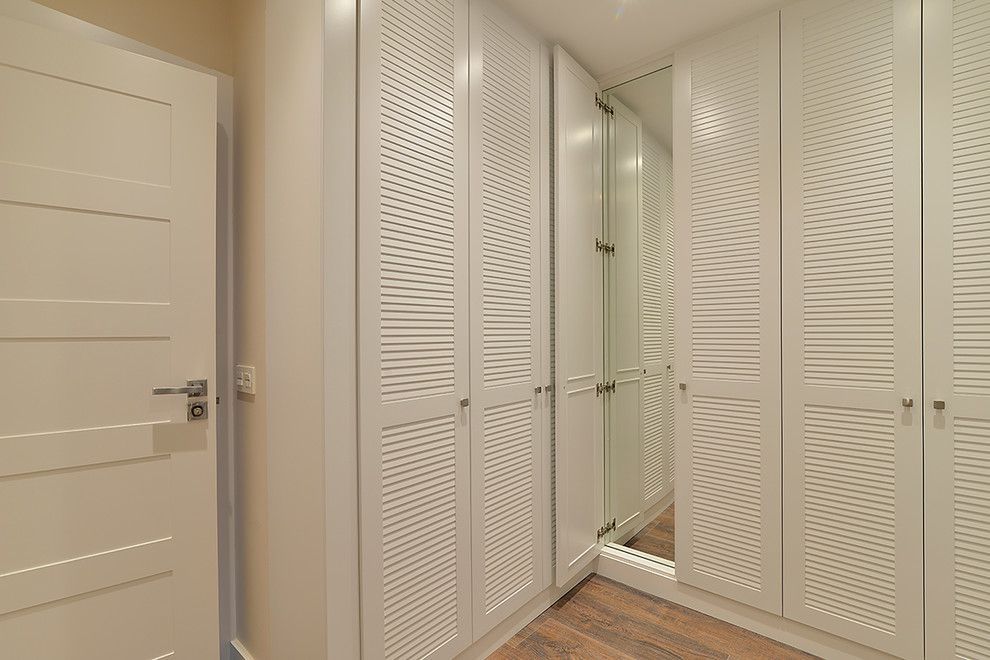 Transitional walk-in wardrobe in Bilbao with louvered cabinets and white cabinets.