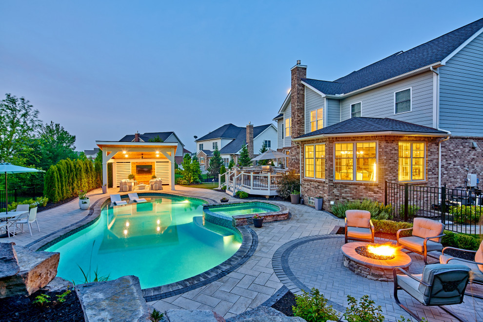 Immagine di una grande piscina design personalizzata dietro casa con un acquascivolo e pavimentazioni in cemento