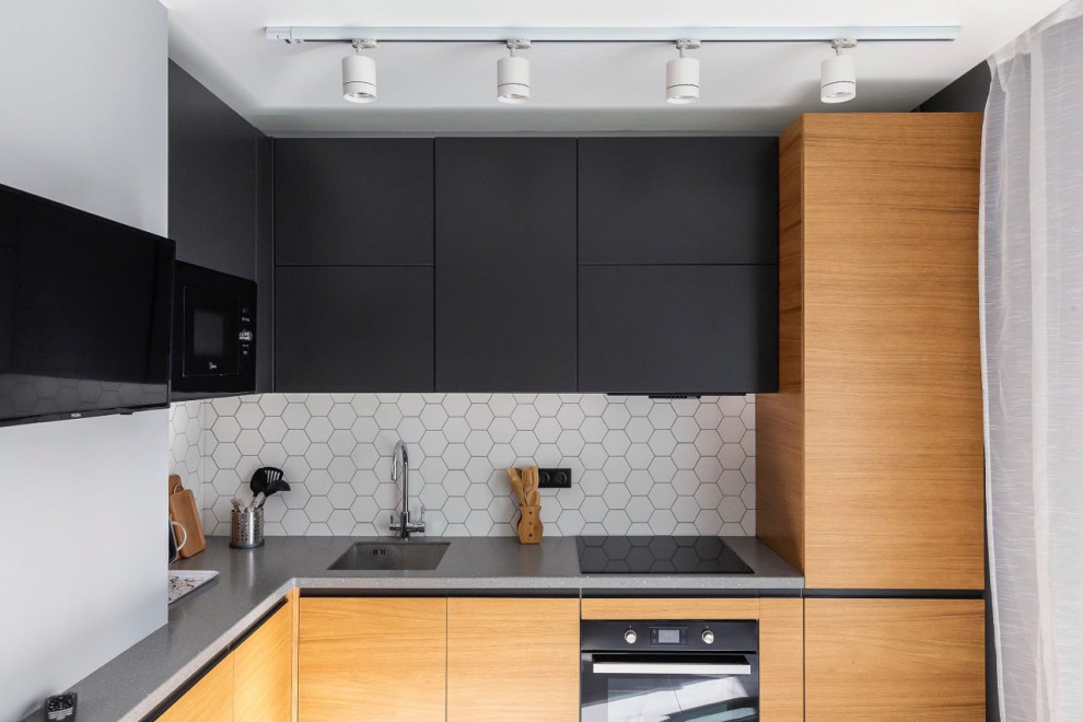 Photo of a contemporary l-shaped separate kitchen in Moscow with an undermount sink, flat-panel cabinets, medium wood cabinets, white splashback, black appliances, no island and grey benchtop.