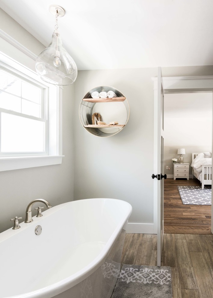 Large country master bathroom in Portland Maine with a freestanding tub, grey walls, porcelain floors and brown floor.
