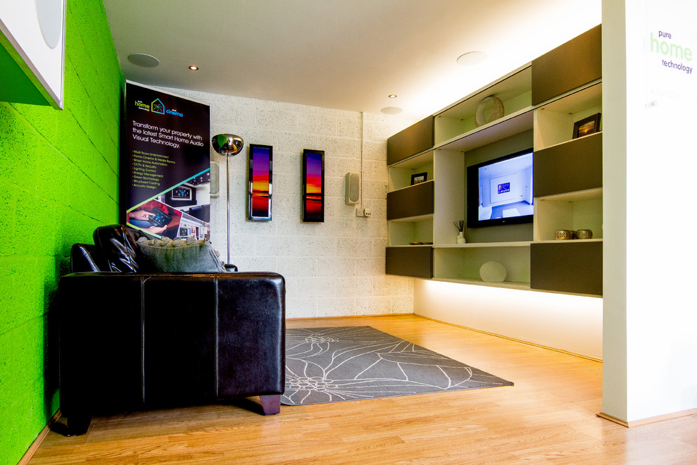 Photo of a modern living room in Hampshire with multi-coloured walls, light hardwood floors and a built-in media wall.