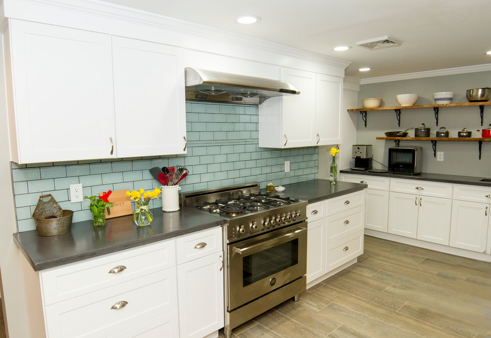 This is an example of a mid-sized transitional galley eat-in kitchen in Philadelphia with a farmhouse sink, shaker cabinets, white cabinets, concrete benchtops, blue splashback, glass tile splashback, stainless steel appliances, porcelain floors and no island.