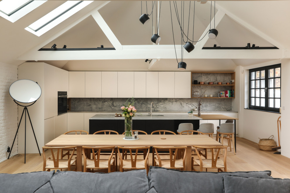 Inspiration for an expansive contemporary l-shaped open plan kitchen in London with an undermount sink, flat-panel cabinets, white cabinets, grey splashback, panelled appliances, with island, beige floor and grey benchtop.