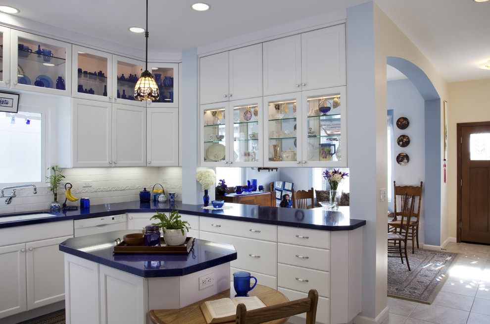 This is an example of a mid-sized eclectic u-shaped separate kitchen in San Diego with glass-front cabinets, an undermount sink, white cabinets, solid surface benchtops, white splashback, porcelain splashback, panelled appliances, ceramic floors, with island, white floor and blue benchtop.