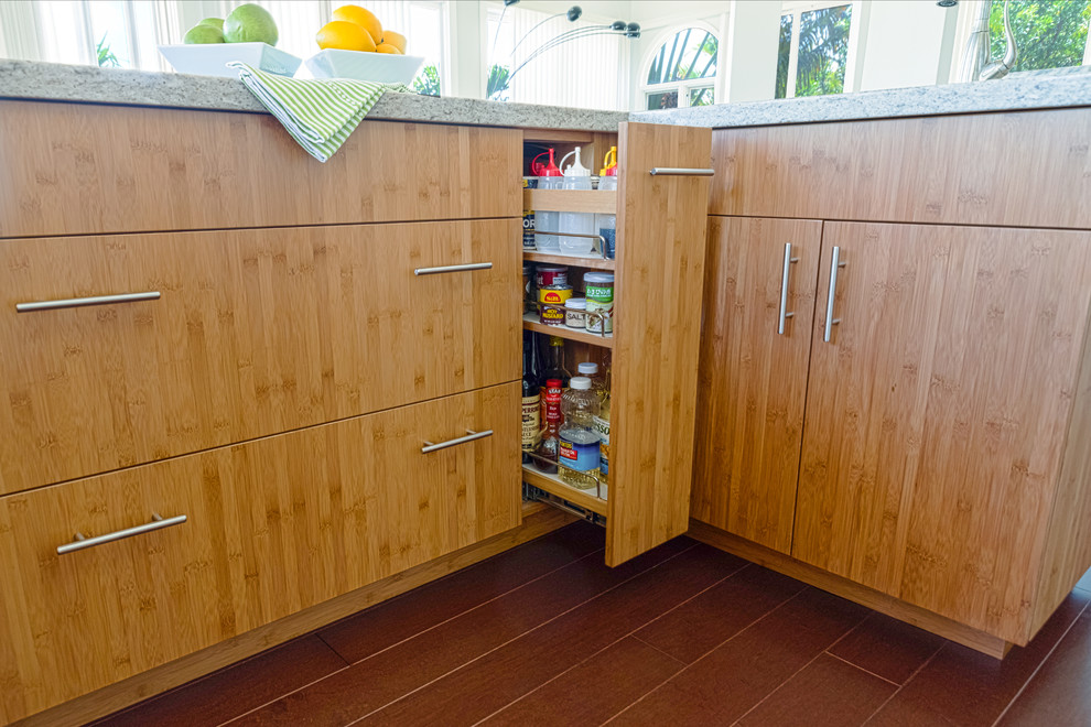This is an example of a large tropical u-shaped eat-in kitchen in Hawaii with with island, an undermount sink, flat-panel cabinets, light wood cabinets, stainless steel appliances and dark hardwood floors.