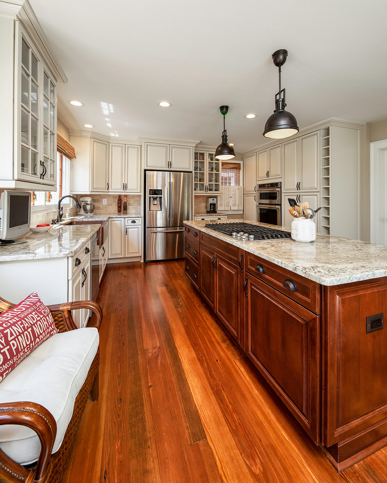 Mid-sized traditional l-shaped eat-in kitchen in Raleigh with a farmhouse sink, raised-panel cabinets, white cabinets, granite benchtops, beige splashback, porcelain splashback, stainless steel appliances, medium hardwood floors, with island, brown floor and beige benchtop.