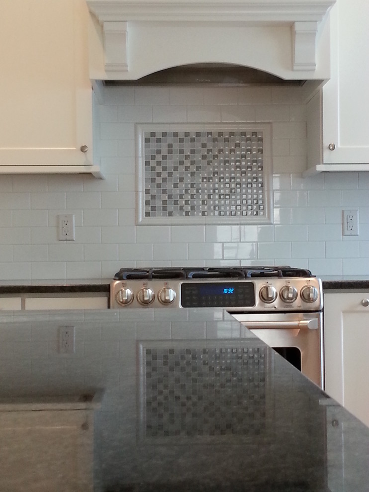 Inspiration for a mid-sized l-shaped light wood floor eat-in kitchen remodel in Newark with a drop-in sink, raised-panel cabinets, white cabinets, granite countertops, white backsplash, subway tile backsplash, stainless steel appliances and an island