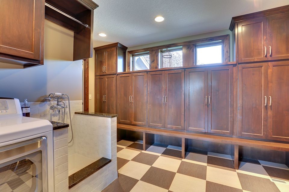 Large country u-shaped laundry room in Minneapolis with beige cabinets, granite benchtops, white splashback and medium hardwood floors.