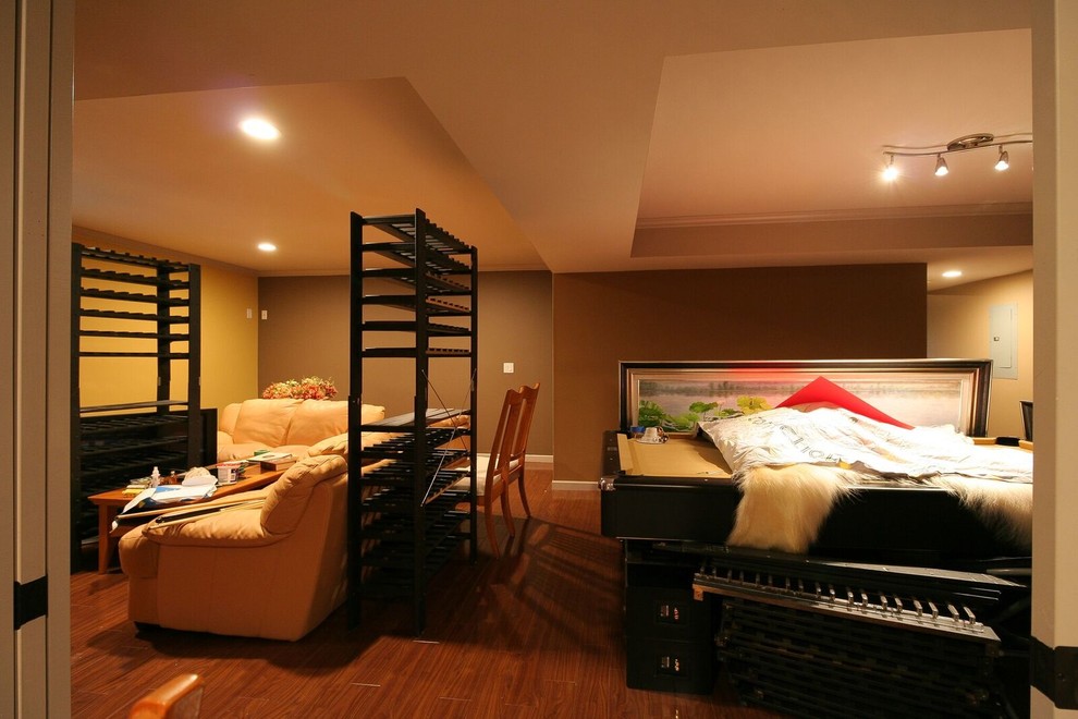 Example of a mid-sized transitional underground medium tone wood floor and brown floor basement design in Vancouver with orange walls, a standard fireplace and a stone fireplace