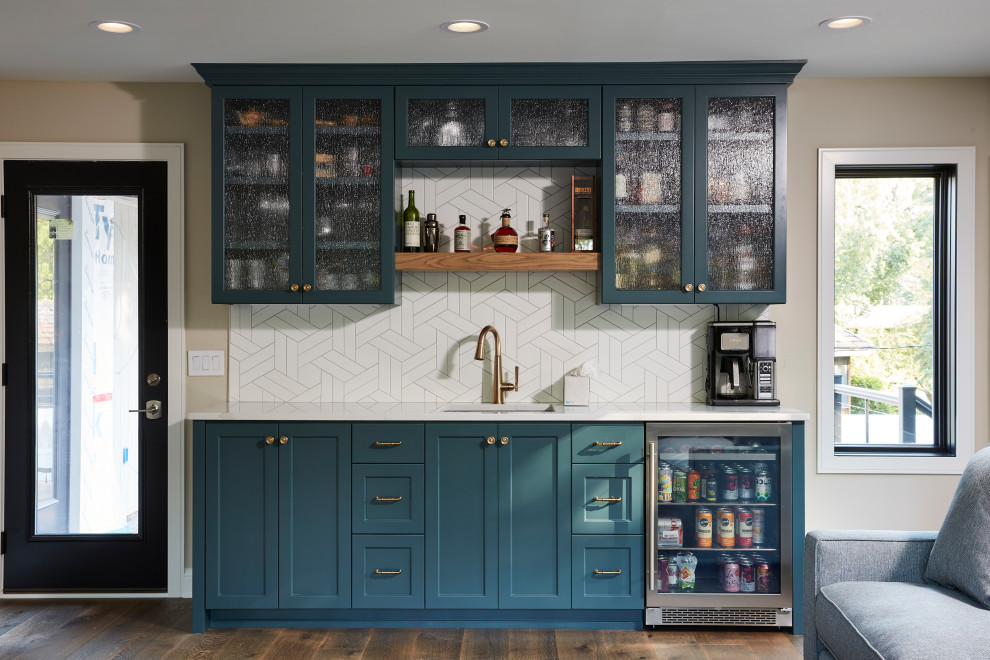 Inspiration for a large contemporary wet bar in Minneapolis with an undermount sink, shaker cabinets, green cabinets, quartz benchtops, white splashback, mosaic tile splashback, medium hardwood floors, brown floor and white benchtop.