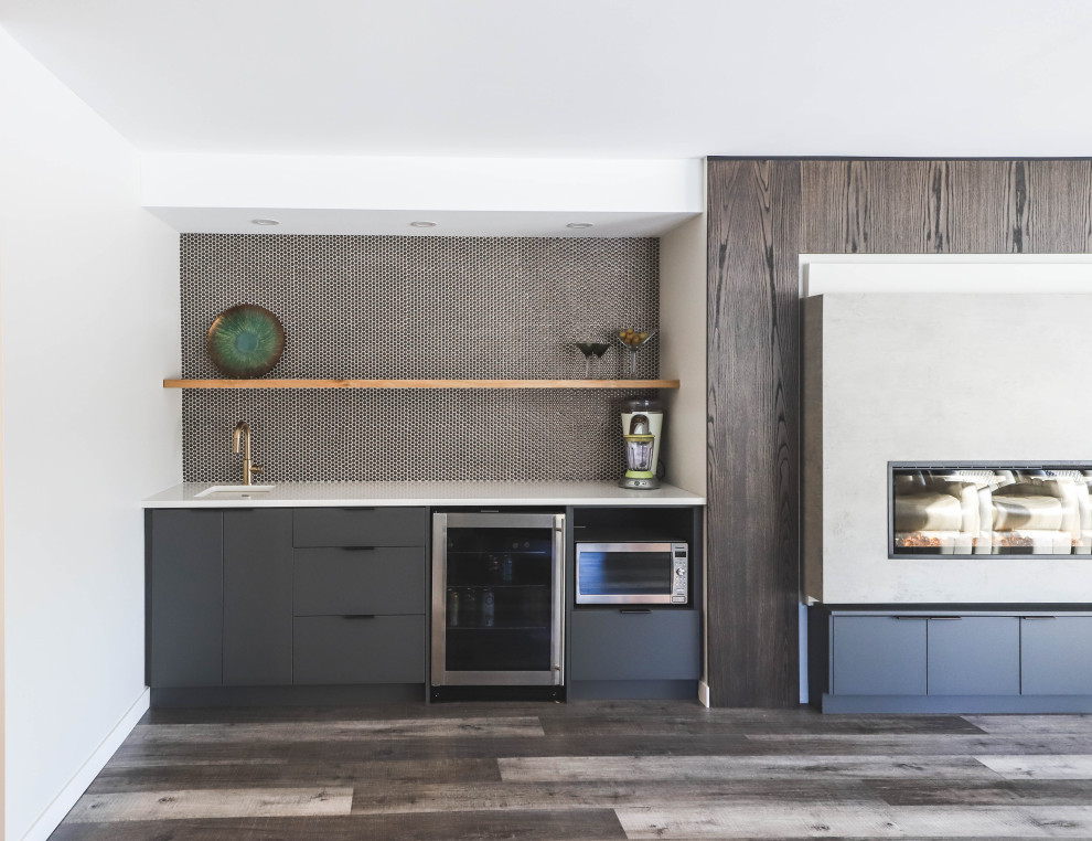 Photo of a mid-sized contemporary single-wall wet bar in Other with an undermount sink, flat-panel cabinets, grey cabinets, solid surface benchtops, black splashback, marble floors, grey floor and white benchtop.