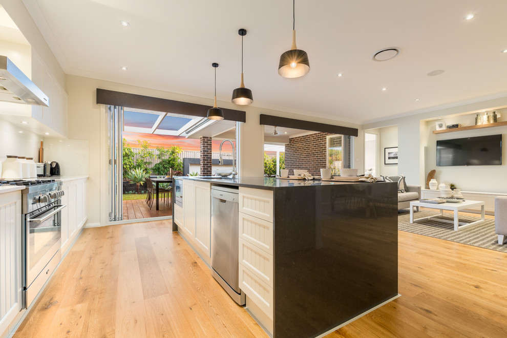 This is an example of a large contemporary galley open plan kitchen in Sydney with an undermount sink, white splashback, glass tile splashback, stainless steel appliances and with island.