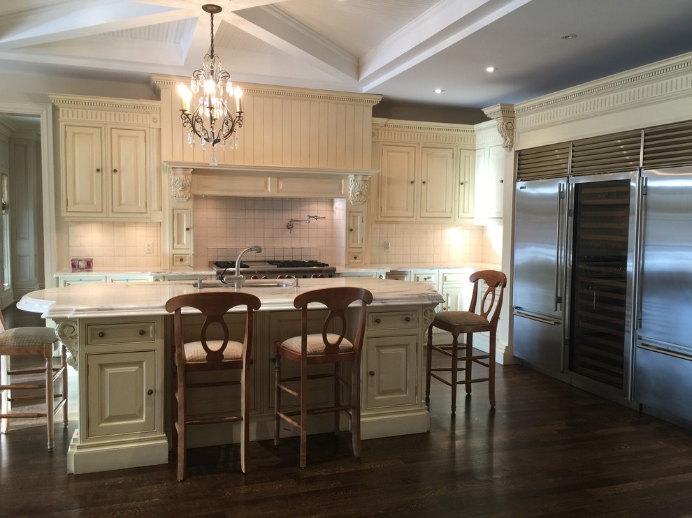 Example of a large transitional l-shaped dark wood floor open concept kitchen design in Toronto with a double-bowl sink, raised-panel cabinets, beige cabinets, white backsplash, stainless steel appliances and an island