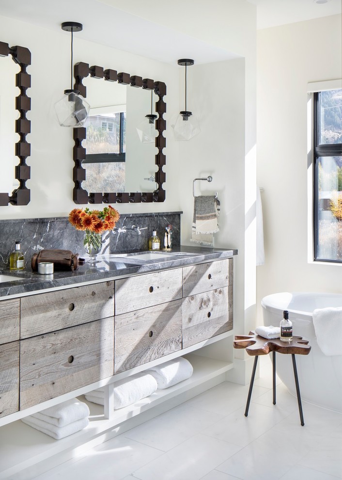 Inspiration for a large rustic master white floor freestanding bathtub remodel with flat-panel cabinets, medium tone wood cabinets, white walls, an undermount sink and gray countertops