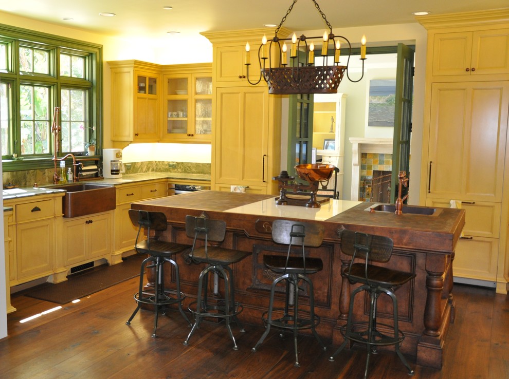 Large traditional l-shaped eat-in kitchen in Los Angeles with a drop-in sink, shaker cabinets, yellow cabinets, wood benchtops, white splashback, stainless steel appliances, dark hardwood floors, with island and brown floor.