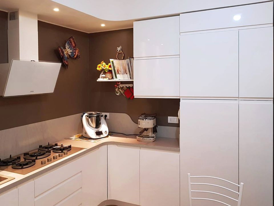 Photo of a mid-sized modern u-shaped separate kitchen in Milan with a drop-in sink, flat-panel cabinets, white cabinets, laminate benchtops, beige splashback, stainless steel appliances, porcelain floors, no island and beige benchtop.