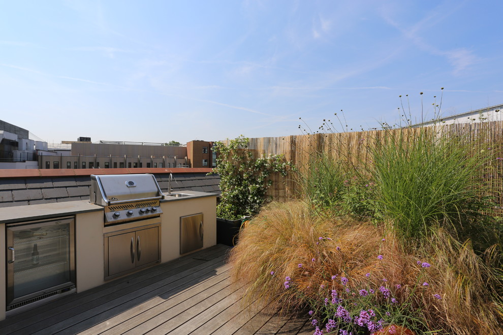 Photo of a mid-sized contemporary rooftop and rooftop deck in London with an outdoor kitchen and no cover.
