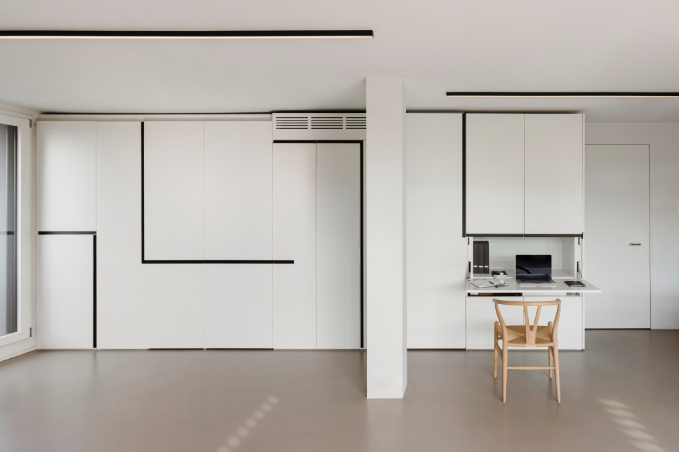 Diseño de estudio contemporáneo de tamaño medio con paredes blancas, suelo de cemento, chimenea lineal, marco de chimenea de metal, escritorio empotrado, suelo gris y bandeja