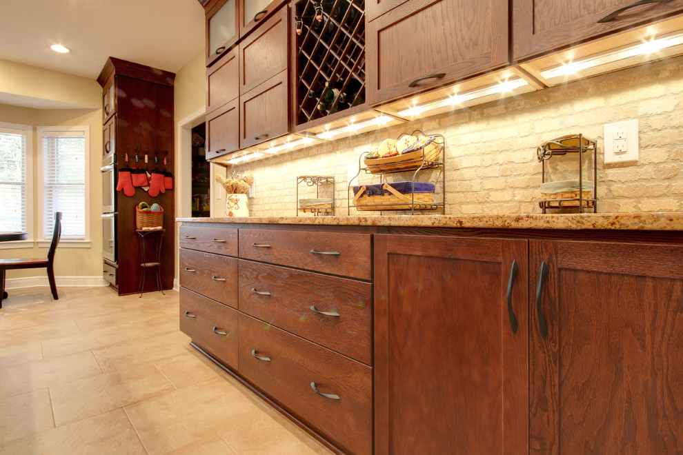 Transitional eat-in kitchen photo in Miami with an undermount sink, shaker cabinets, brown cabinets, granite countertops, beige backsplash, stone tile backsplash and stainless steel appliances