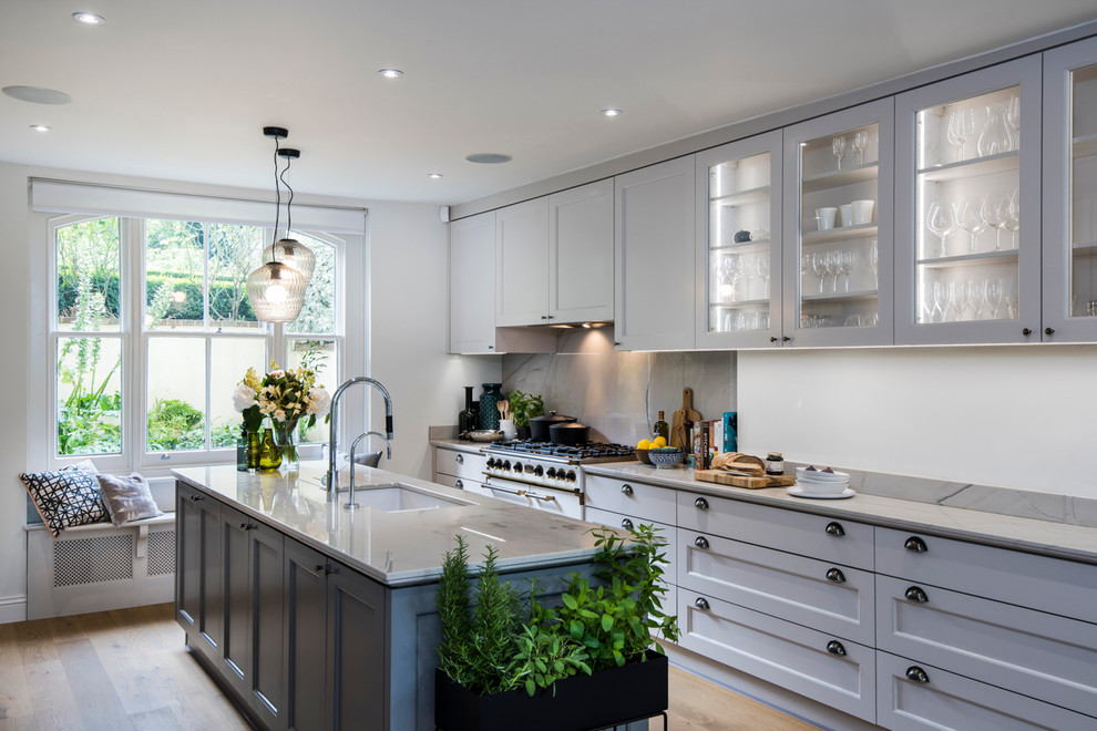 Design ideas for a transitional galley kitchen in London with an undermount sink, recessed-panel cabinets, grey cabinets, light hardwood floors and with island.