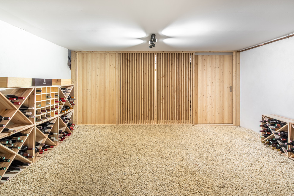 Idee per una grande cantina minimalista con moquette, portabottiglie a scomparti romboidali e pavimento beige
