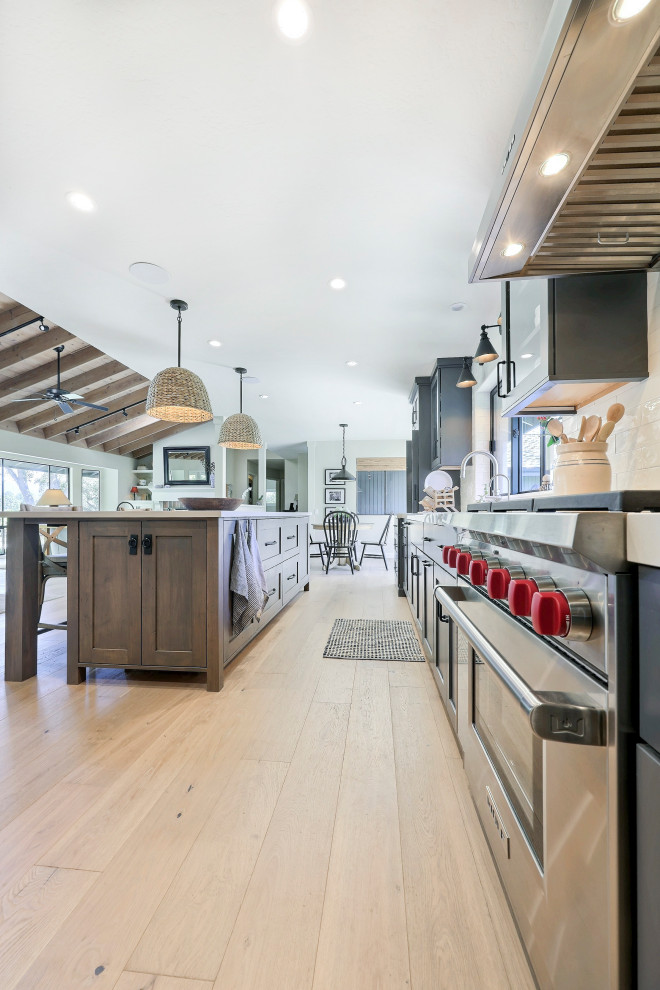 Inspiration for a mid-sized transitional l-shaped laminate floor open concept kitchen remodel with a double-bowl sink, flat-panel cabinets, gray cabinets, quartz countertops, white backsplash, ceramic backsplash, stainless steel appliances, an island and white countertops