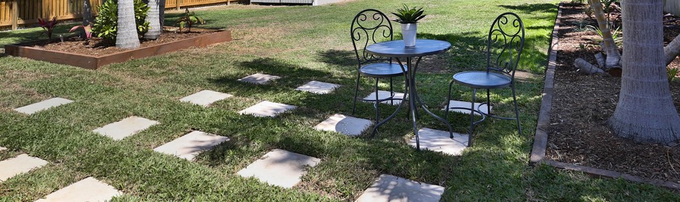 This is an example of a small backyard patio in Townsville with natural stone pavers and no cover.