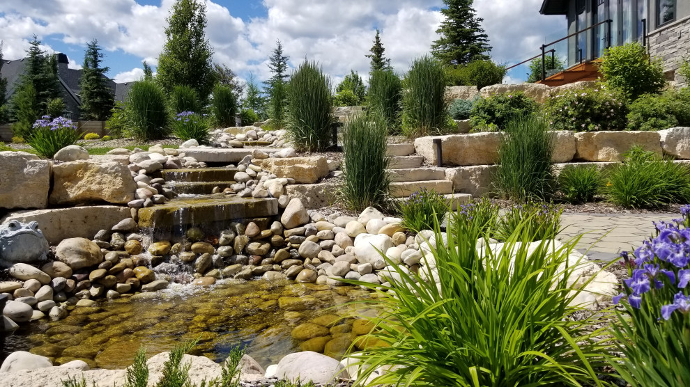 Photo of a large transitional full sun backyard river rock formal garden in Calgary for spring.