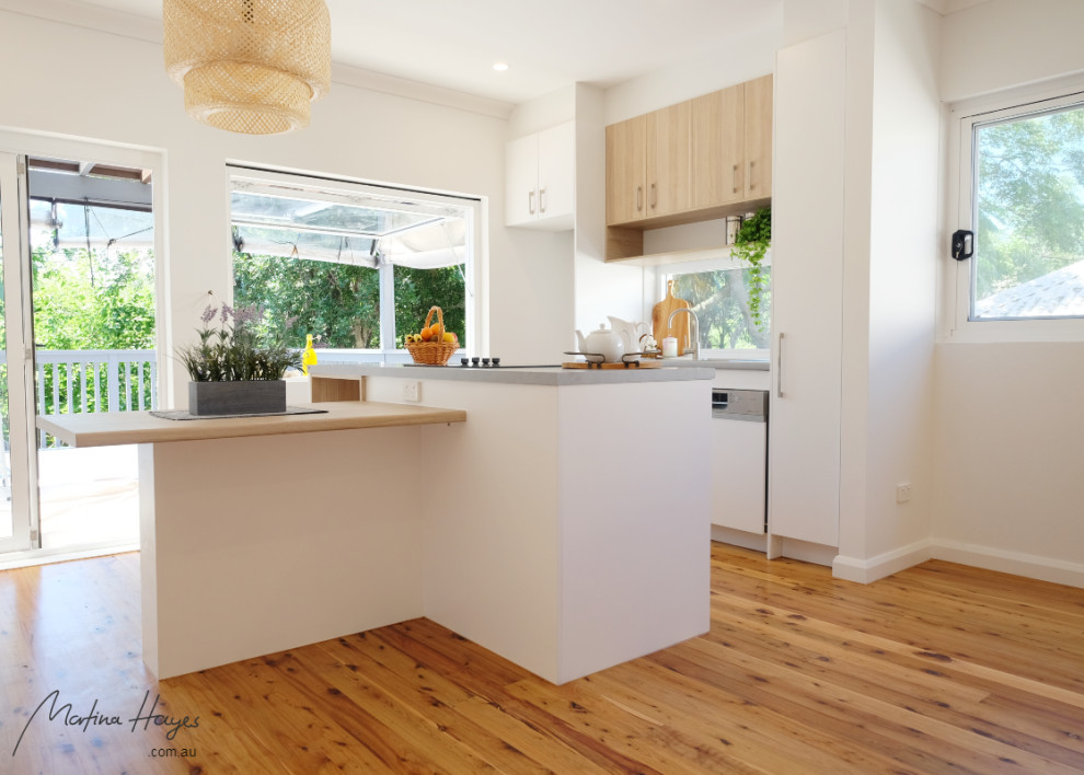 Kleine, Zweizeilige Moderne Wohnküche mit flächenbündigen Schrankfronten, hellen Holzschränken, Laminat-Arbeitsplatte, Rückwand-Fenster, Küchengeräten aus Edelstahl, zwei Kücheninseln, grauer Arbeitsplatte, Einbauwaschbecken, braunem Holzboden und braunem Boden in Sydney