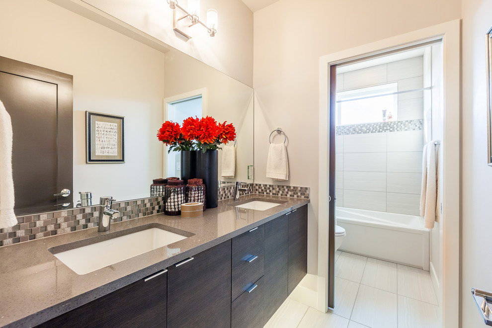 Small modern bathroom in Seattle with flat-panel cabinets, dark wood cabinets, an alcove tub, a shower/bathtub combo, a one-piece toilet, black tile, black and white tile, gray tile, white tile, mosaic tile, white walls, vinyl floors, a vessel sink and terrazzo benchtops.