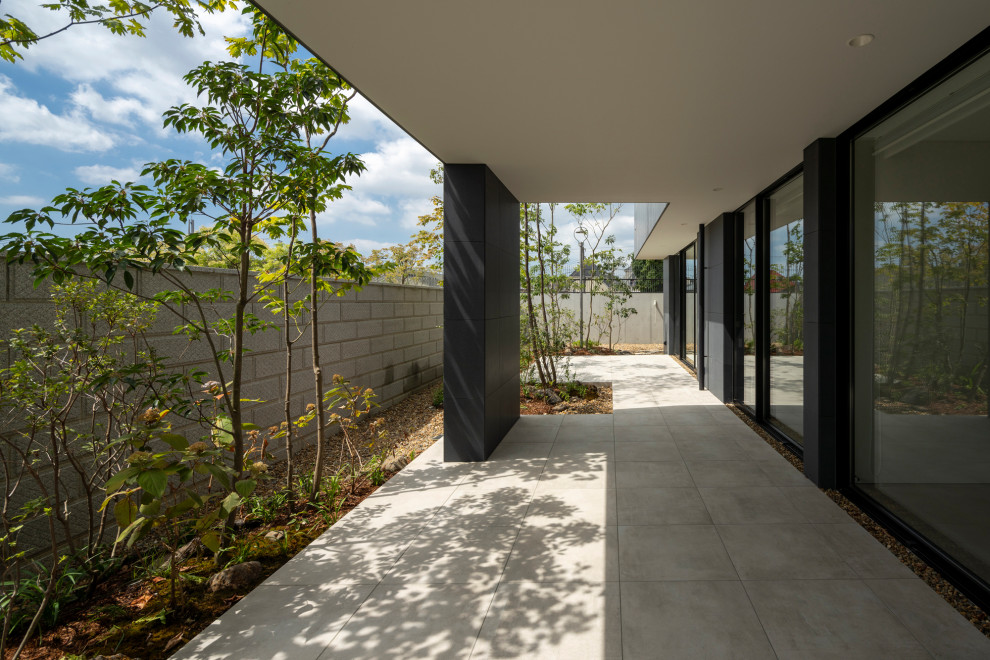 На фото: огромный двор на боковом дворе в стиле модернизм с покрытием из плитки и навесом