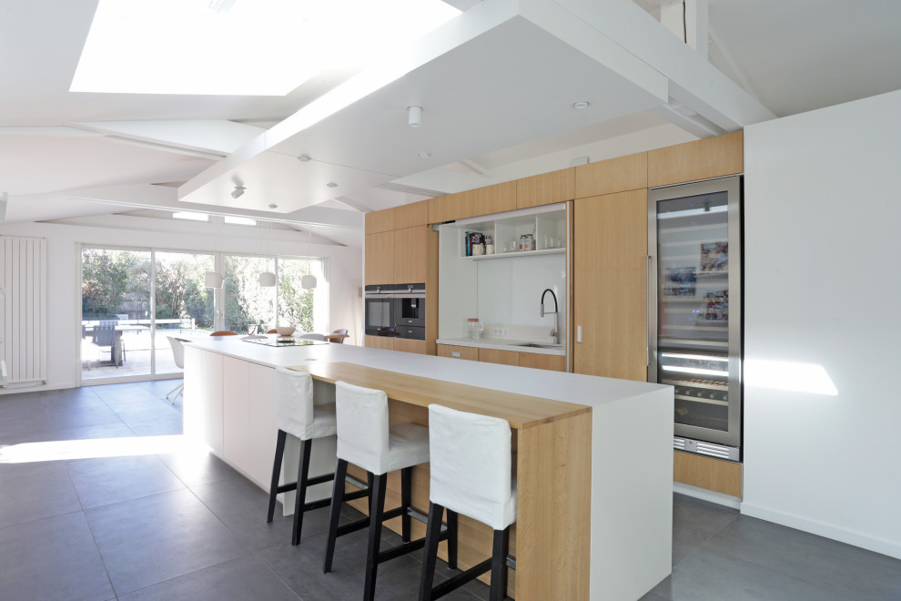 Inspiration for a large contemporary galley kitchen/diner in Bordeaux with a submerged sink, all styles of cabinet, light wood cabinets, engineered stone countertops, white splashback, mirror splashback, integrated appliances, ceramic flooring, an island, grey floors, white worktops and exposed beams.