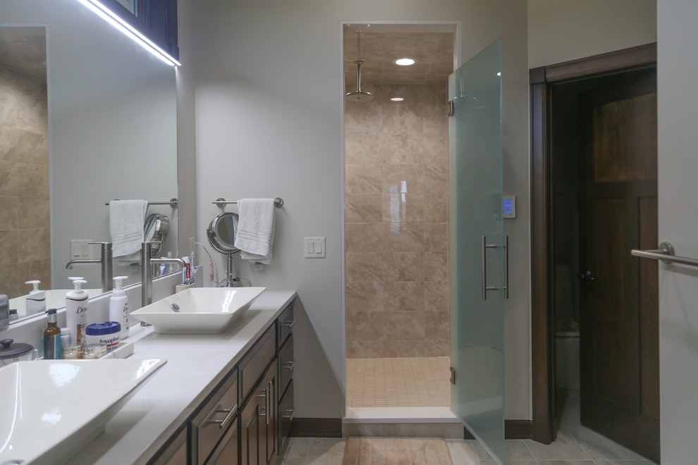 Inspiration for a mid-sized transitional master beige tile and porcelain tile porcelain tile and beige floor alcove shower remodel with raised-panel cabinets, medium tone wood cabinets, a two-piece toilet, white walls, a vessel sink, quartzite countertops and a hinged shower door