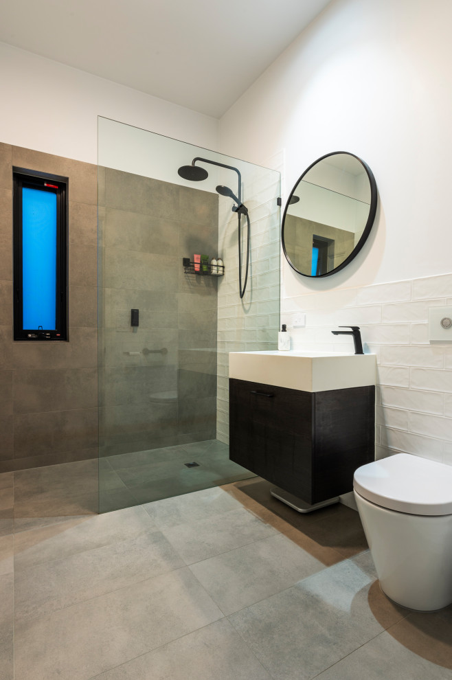 Large contemporary grey and white bathroom in Melbourne with flat-panel cabinets, black cabinets, a walk-in shower, a wall mounted toilet, white tiles, metro tiles, white walls, cement flooring, a submerged sink, limestone worktops, grey floors, an open shower, white worktops, a single sink and a built in vanity unit.