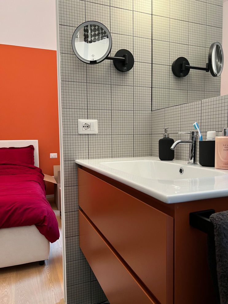Inredning av ett modernt mellanstort vit vitt en-suite badrum, med orange skåp, en toalettstol med separat cisternkåpa, svart och vit kakel, porslinskakel, vita väggar, klinkergolv i porslin, ett integrerad handfat och svart golv