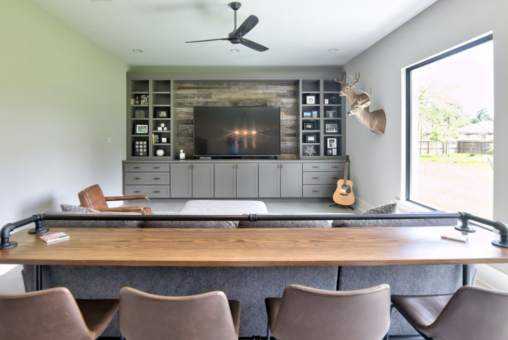 Inspiration for a large country open concept home theatre in Houston with beige walls, concrete floors, a built-in media wall and grey floor.