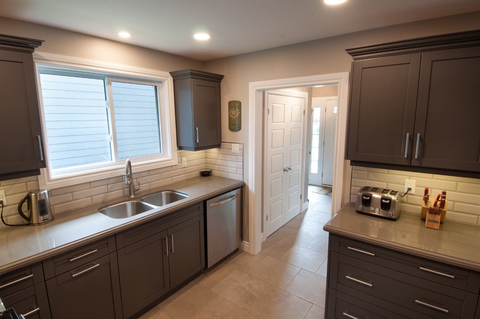 Mid-sized transitional u-shaped ceramic tile and beige floor enclosed kitchen photo in Toronto with a double-bowl sink, shaker cabinets, dark wood cabinets, quartzite countertops, beige backsplash, subway tile backsplash, stainless steel appliances and no island