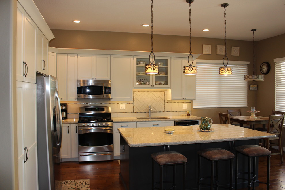 Open concept kitchen - mid-sized transitional l-shaped dark wood floor and brown floor open concept kitchen idea in Phoenix with an undermount sink, shaker cabinets, white cabinets, granite countertops, white backsplash, subway tile backsplash, stainless steel appliances and an island