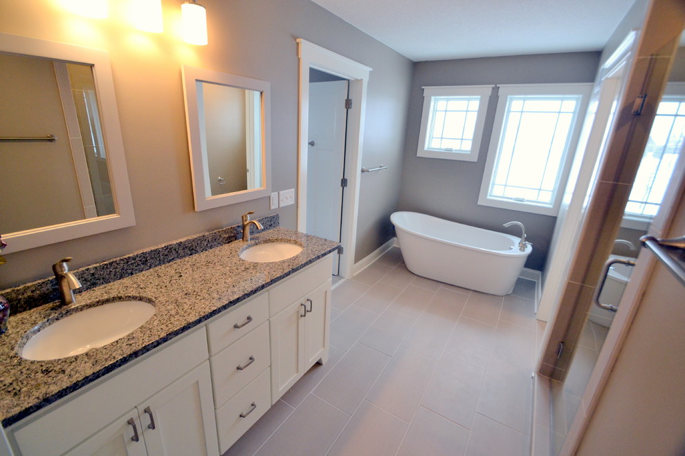 Photo of a contemporary bathroom in Minneapolis with an undermount sink, shaker cabinets, white cabinets, granite benchtops, a freestanding tub, an alcove shower, a two-piece toilet, beige tile and ceramic tile.