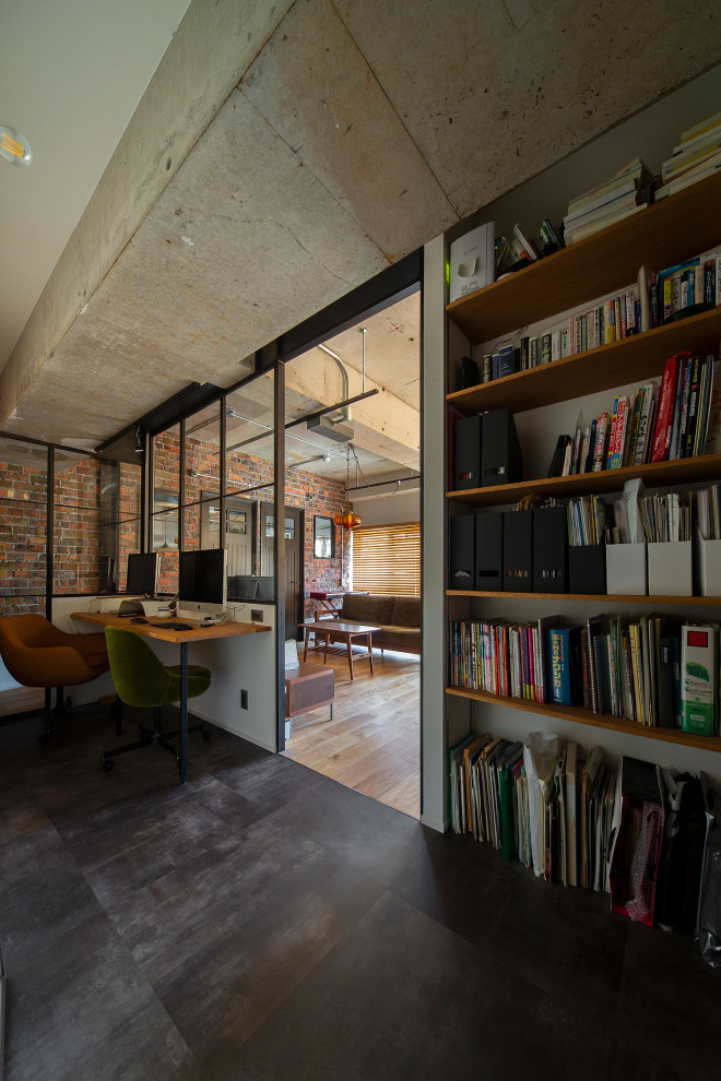 Пример оригинального дизайна: рабочее место в стиле лофт с белыми стенами, полом из винила, отдельно стоящим рабочим столом, серым полом и балками на потолке без камина
