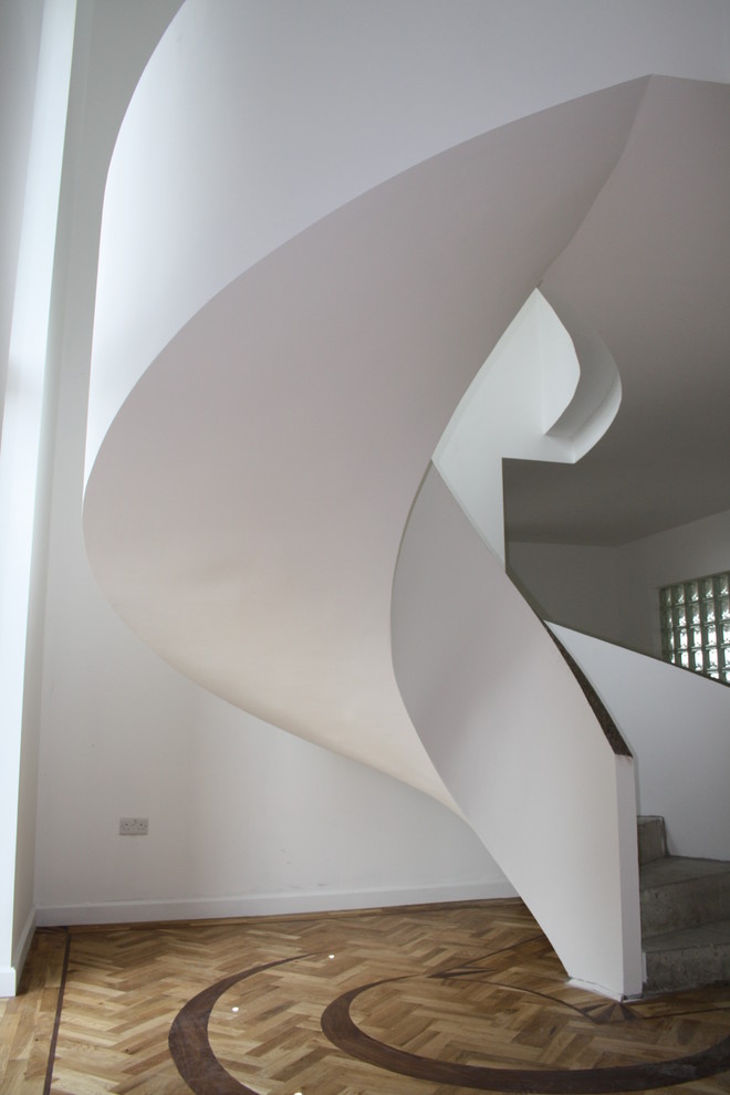 Mid-sized contemporary concrete spiral staircase in Other with concrete risers.