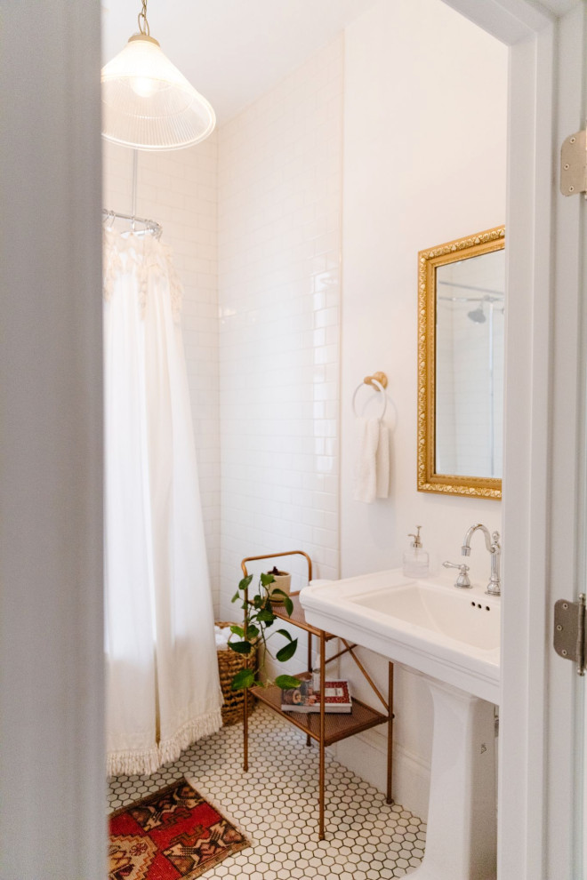 На фото: ванная комната в стиле шебби-шик с душем над ванной, белыми стенами, раковиной с пьедесталом, белым полом, шторкой для ванной и тумбой под одну раковину
