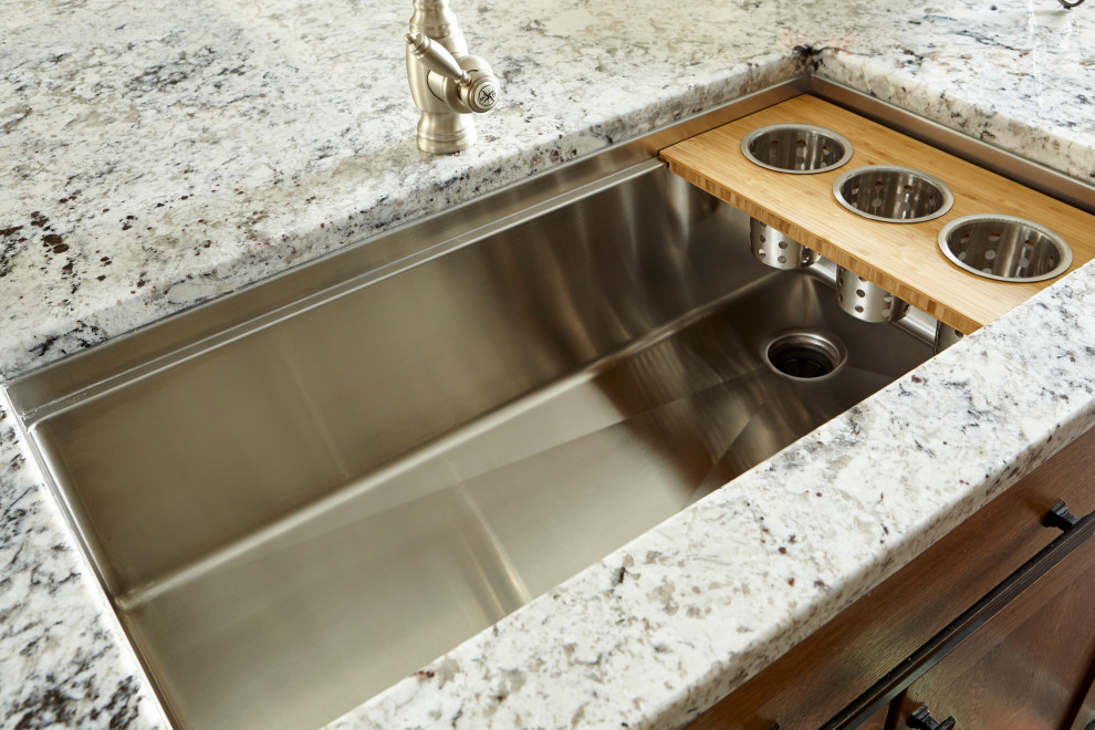 Inspiration for a large rustic l-shaped eat-in kitchen remodel in Cincinnati with an undermount sink, shaker cabinets, brown cabinets, granite countertops, white backsplash, ceramic backsplash, stainless steel appliances, an island and multicolored countertops
