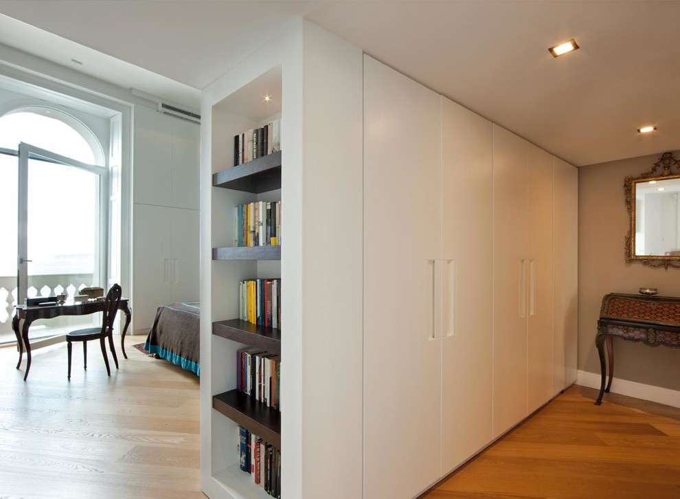 Large contemporary gender-neutral built-in wardrobe in Paris with medium hardwood floors and white cabinets.