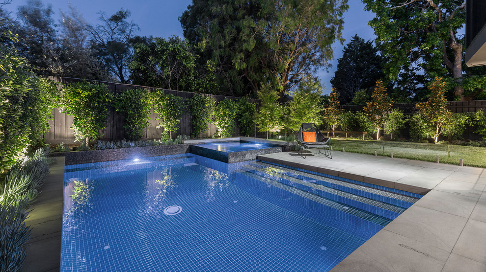 This is an example of a contemporary backyard rectangular pool in Melbourne with a hot tub and concrete pavers.